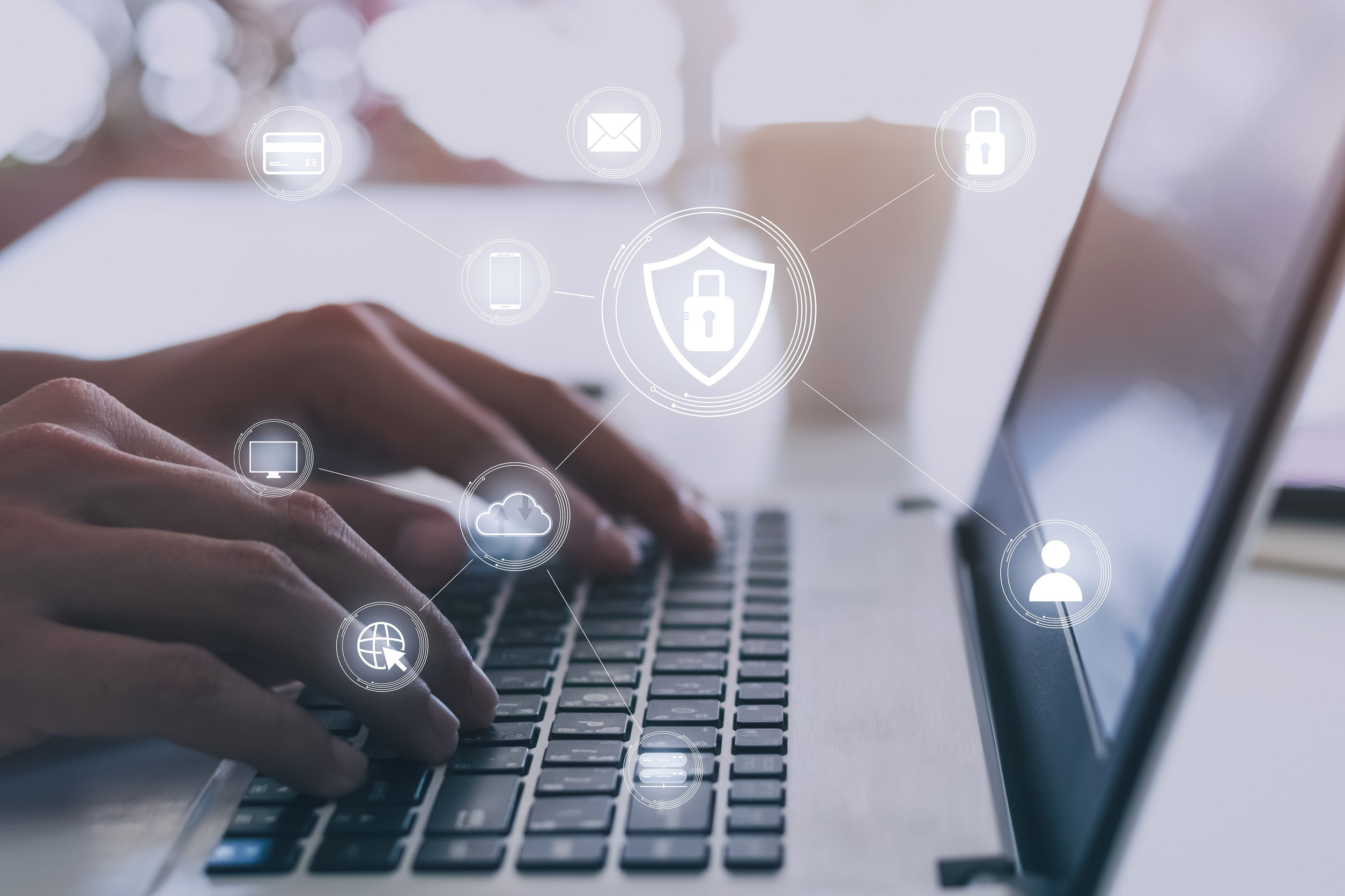 Close-up of a person using a laptop with digital security and cloud technology icons displayed on screen, representing secure access, data protection, and modern cloud-based network security for businesses.